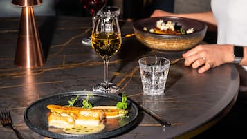 A dining table with a plate of food, a glass of wine, and a candle.