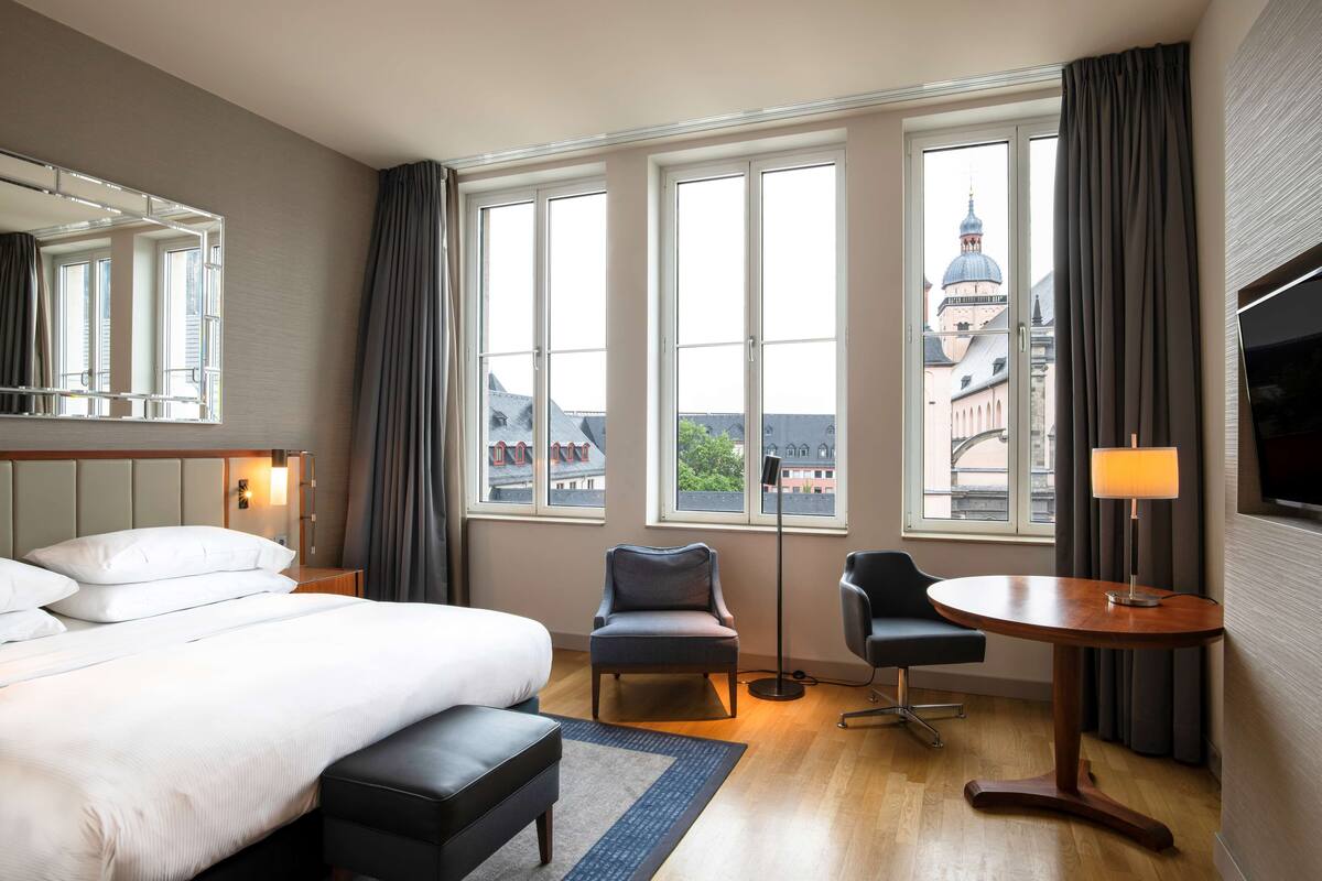 Una habitación de hotel con una cama grande, un escritorio, una silla y un televisor.