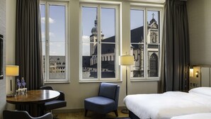 Una habitación de hotel con un ventanal grande, una cama, un escritorio y una silla.