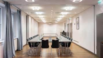 A conference room with a long table, chairs, and a projector screen.