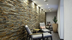 Un área de descanso moderna con pared de piedra, asientos y una gran planta en maceta.
