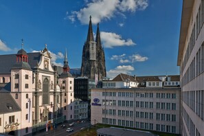 Un hôtel à la façade moderne, arborant le logo Hilton bien en évidence, et offrant une vue sur une cathédrale historique en arrière-plan.