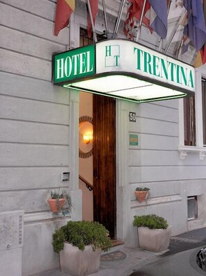 A hotel entrance with a green sign reading "HOTEL TRENTINA" and the number "50" on the wall. - Hotel Trentina (Milan)