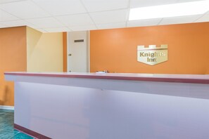 Un comptoir d’accueil avec une enseigne « Knights Inn », une porte et un sol carrelé.