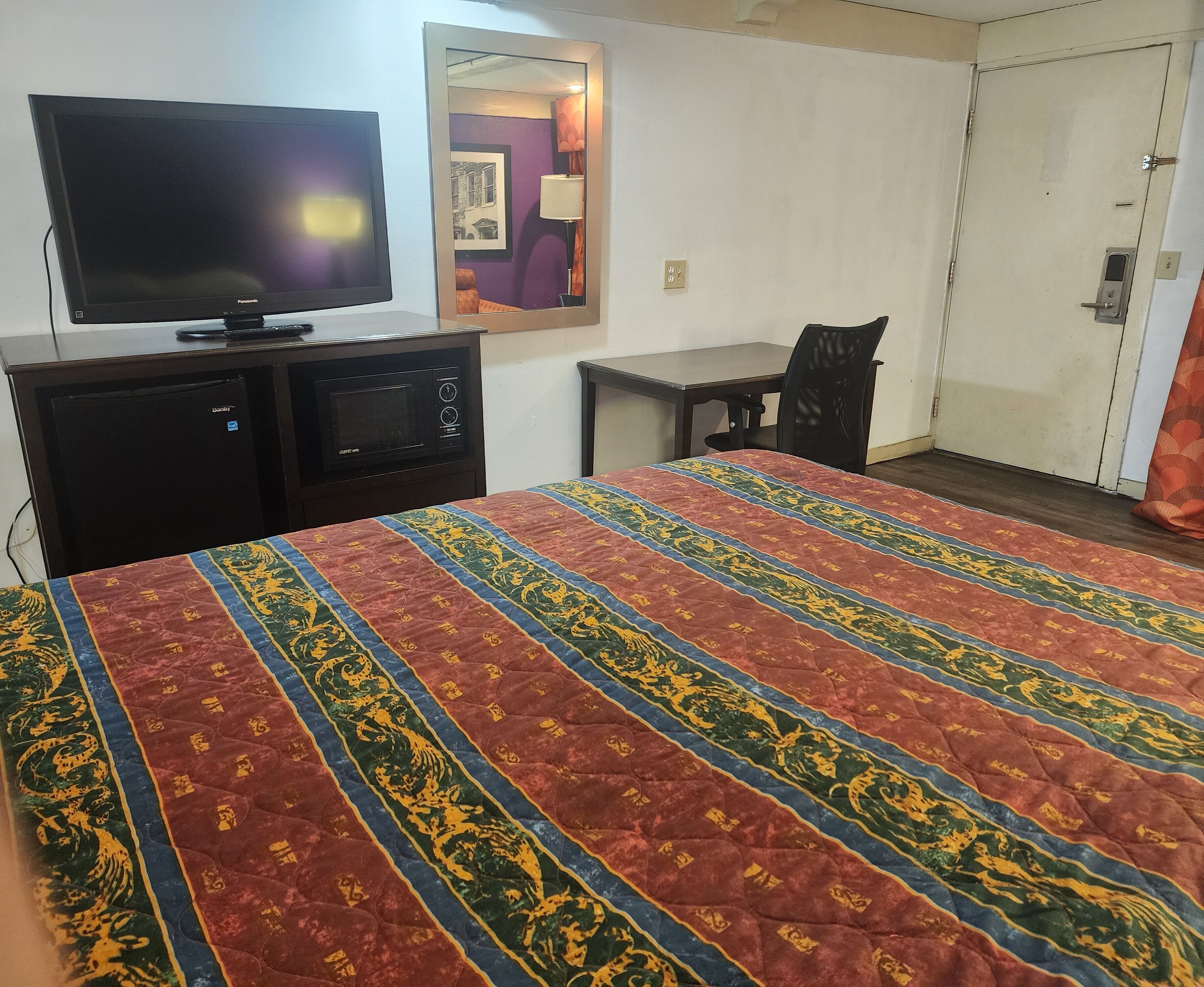 Ein Hotelzimmer mit Bett, Fernseher, Schreibtisch und Stuhl.