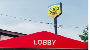 A Sunrise Inn with a red awning labeled "Lobby" and a stone facade. - Travelodge by Wyndham Elkton University Area (Elkton)