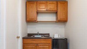A compact kitchen with wooden cabinets, a stainless steel refrigerator, and a sink. - Travelodge by Wyndham Elkton University Area (Elkton)