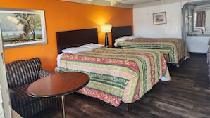 A hotel room with two beds, a sofa, a small table, and a painting on the wall. - Travelodge by Wyndham Elkton University Area (Elkton)