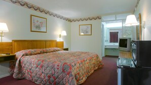 A hotel room with a large bed, a television, and a refrigerator.
