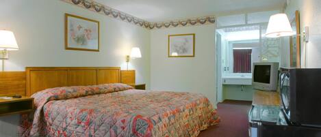 Quarto de hotel com uma cama grande, televisão e frigorífico.