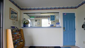 A reception area with a blue door, a wooden display stand, and a patterned rug.