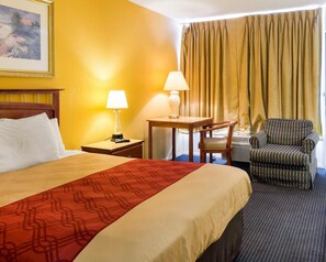 A hotel room with a bed, two bedside tables with lamps, a chair, and a window with curtains. - Econo Lodge Petersburg - Fort Lee (Petersburg)