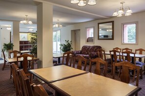 Een eethoek met houten tafels en stoelen, een bloemenbank en hanglampen.