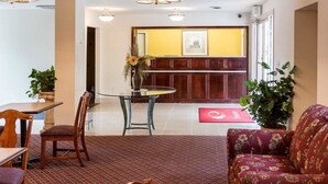 A dining area with a glass table, wooden chairs, and a red carpet. There is a wooden bench with a floral cushion in the foreground. - Econo Lodge Petersburg - Fort Lee (Petersburg)
