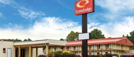 An EconoLodge hotel with a red sign, a parking lot, and a building with a red roof.