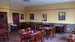 A conference room with multiple wooden tables and chairs, carpeted floor, and framed pictures on the walls. - King's Inn (Belle Fourche)