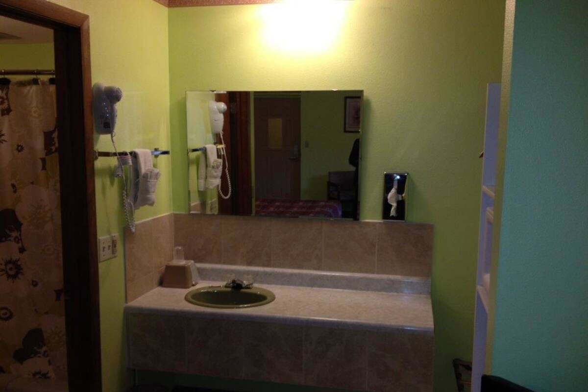 A bathroom with a sink, mirror, and two hair dryers mounted on the wall.