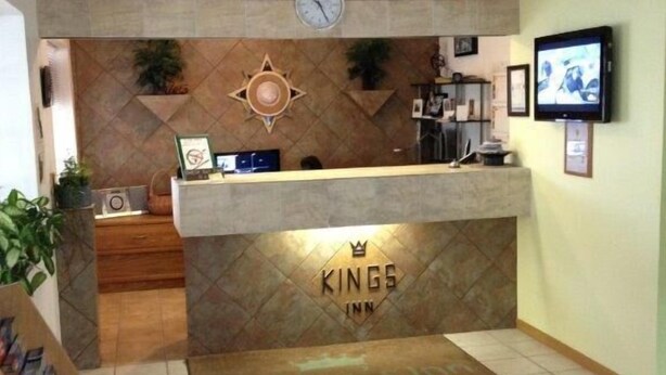 A reception area with a clock, a television, and a sign that reads "Kings Inn". - King's Inn (Belle Fourche)