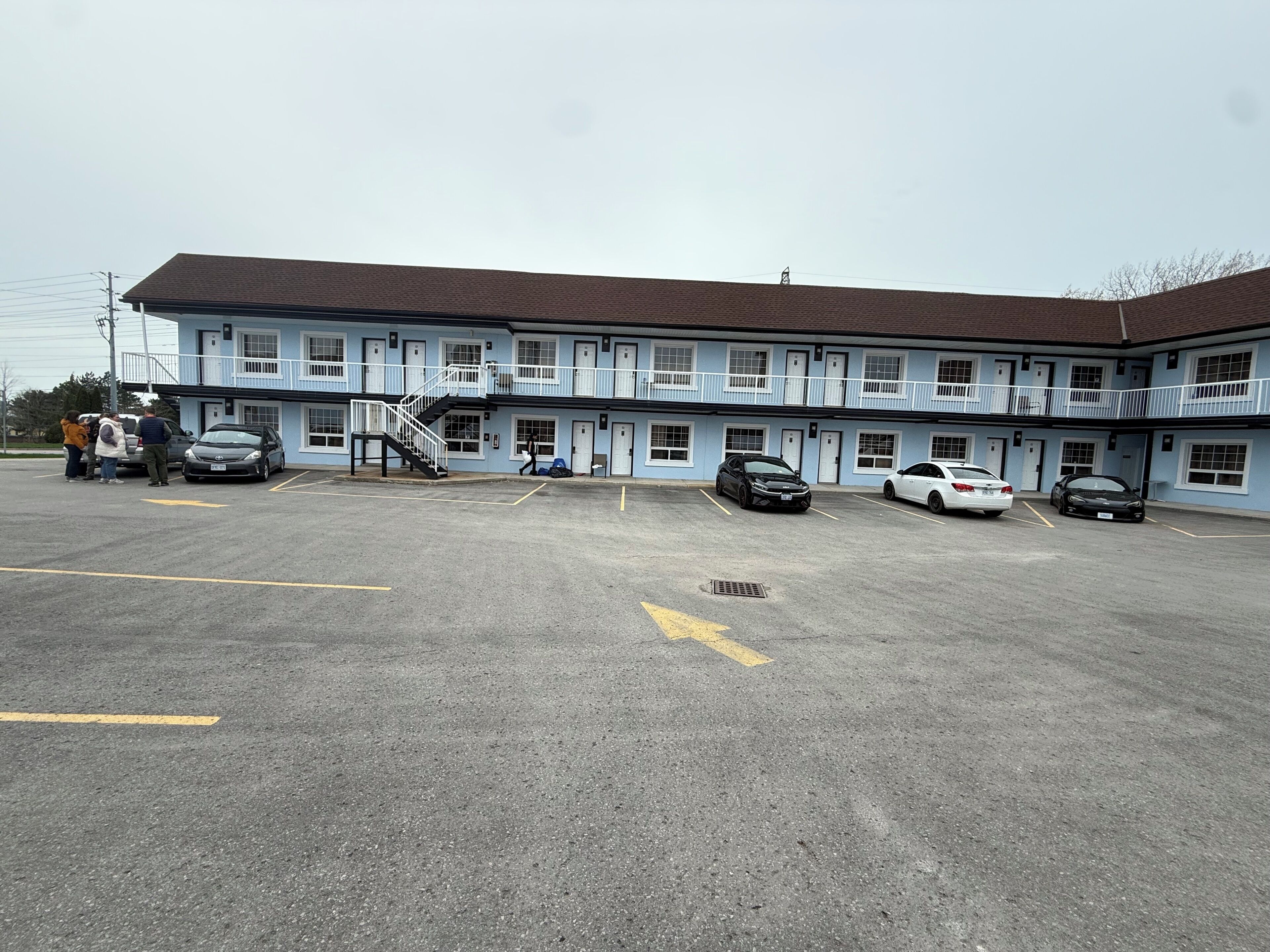 A motel with a two-story structure, a parking lot, and a staircase leading to the upper floor.