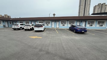 A parking lot with several cars, a building with blue and white exterior, and a tall building in the background.