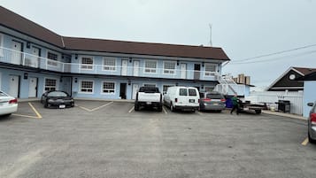 Un motel con estacionamiento, una camioneta blanca y un automóvil estacionado al frente.