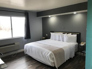 Een moderne hotelkamer met een groot bed, een nachtkastje met lamp, een raam met gordijnen en een wandradiator.
