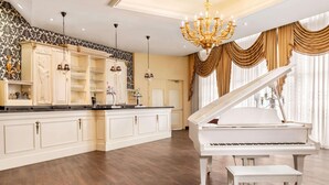 A spacious room with a grand piano, elegant cabinetry, and a chandelier.