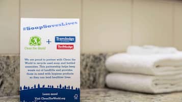 A bathroom with a sign promoting #SoapSavesLives, Clean the World, and TraveLodge by Wyndham.