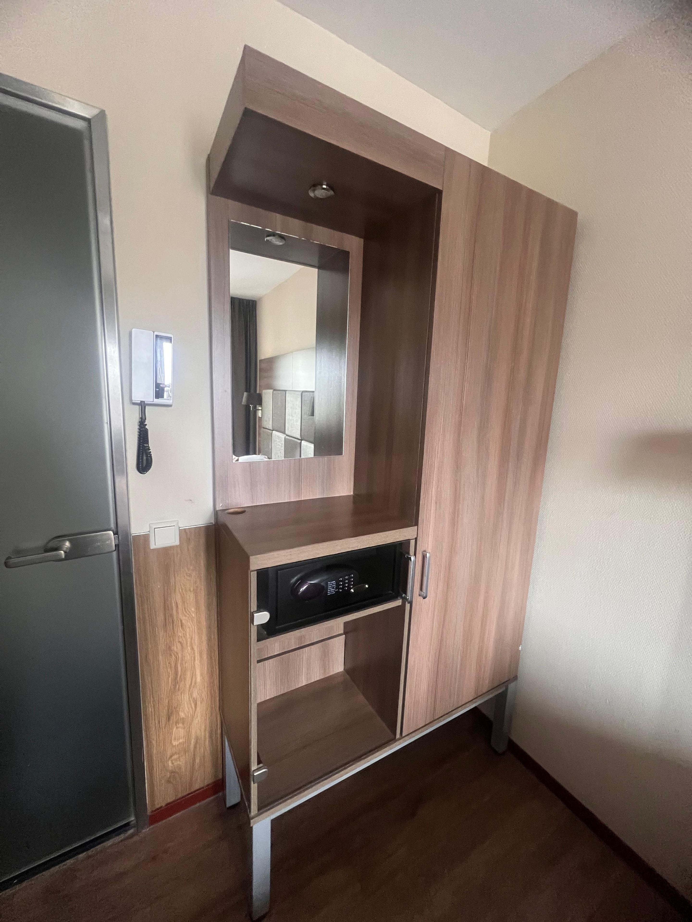 A room with a built-in wardrobe, a mirror, and a microwave.