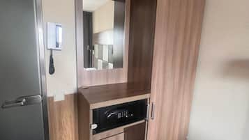 A room with a built-in wardrobe, a mirror, and a microwave.