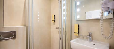 A modern bathroom with a glass-enclosed shower, a white sink, and a towel rack.
