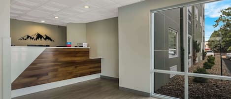A reception area with a wooden reception desk, a mountain mural, and a large sliding glass door leading to a landscaped outdoor area.