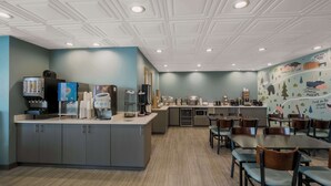 A modern restaurant with a central island, seating area, and a wall with travel-themed murals. - SureStay Plus Hotel by Best Western Sevierville (Sevierville)