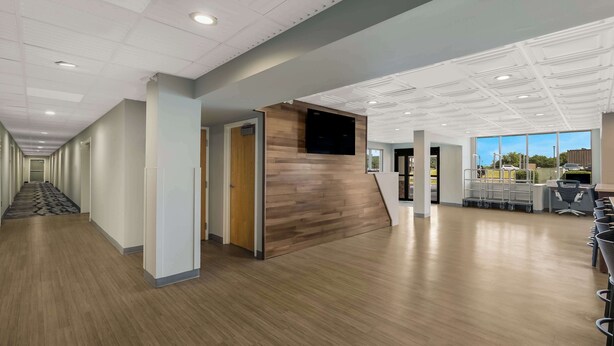 A spacious hallway with a wooden reception desk, a flat-screen TV, and a view of the outdoors through large windows. - SureStay Plus Hotel by Best Western Sevierville (Sevierville)