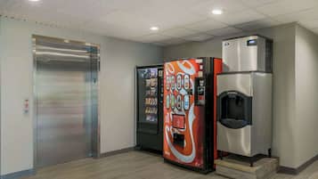 A hotel lobby with a metallic elevator, a Coca-Cola branded beverage dispenser, and an ice dispenser.