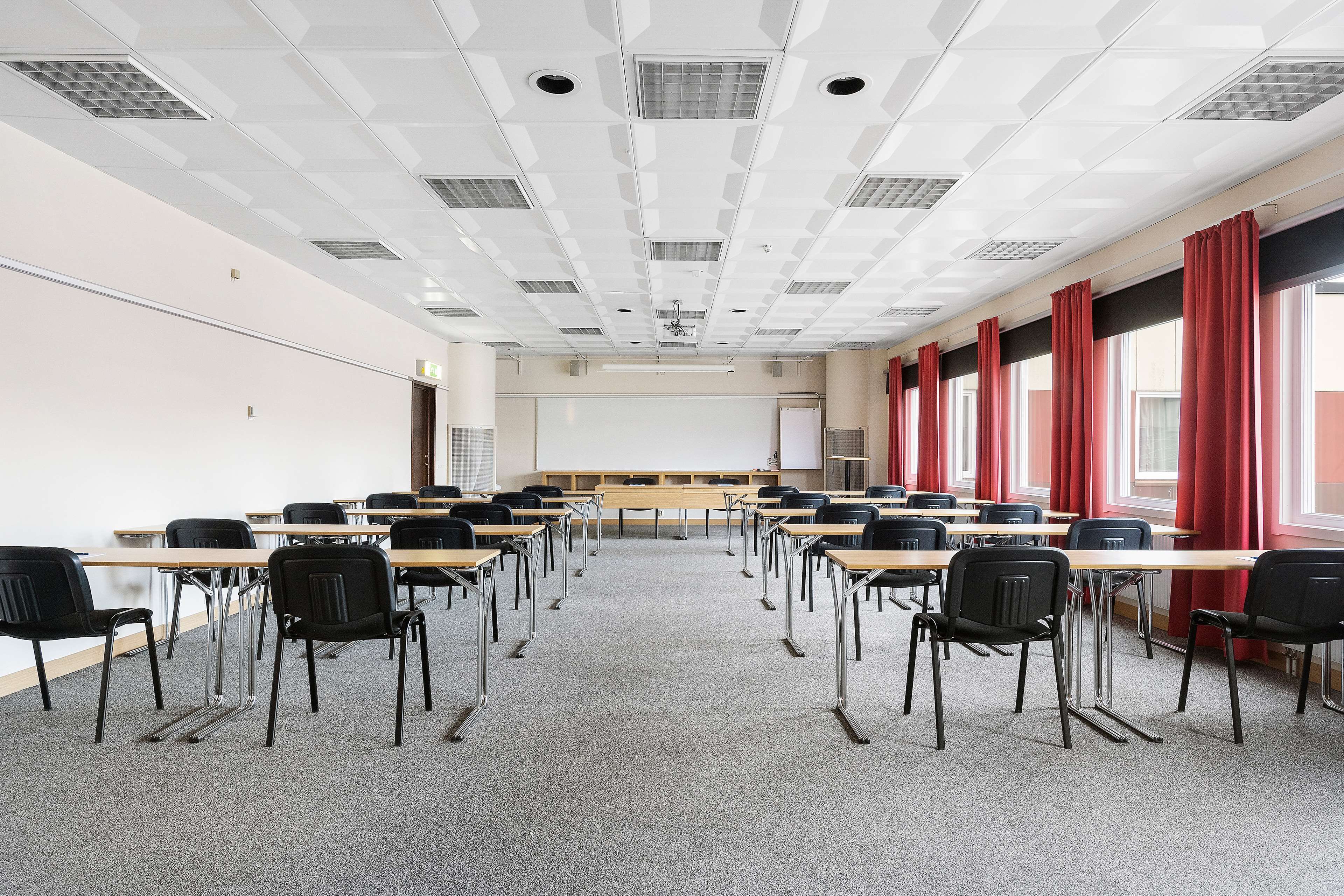 A classroom with rows of desks and chairs, a projector screen, and a whiteboard.