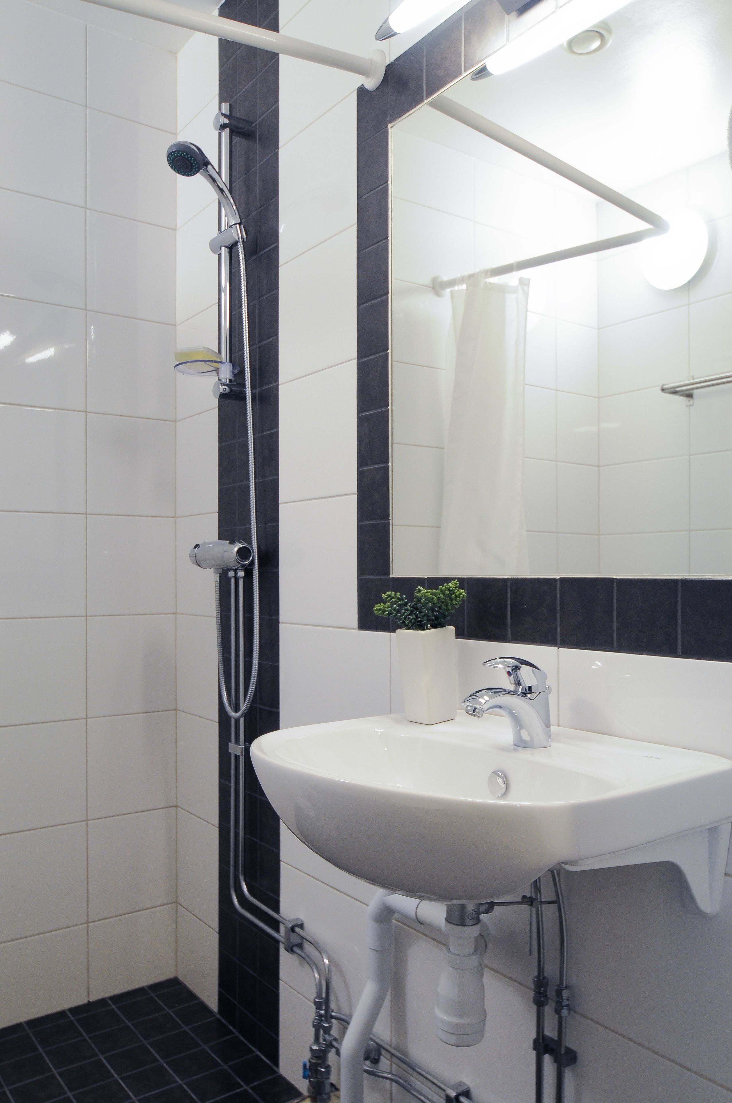 A bathroom with a shower, sink, and mirror.