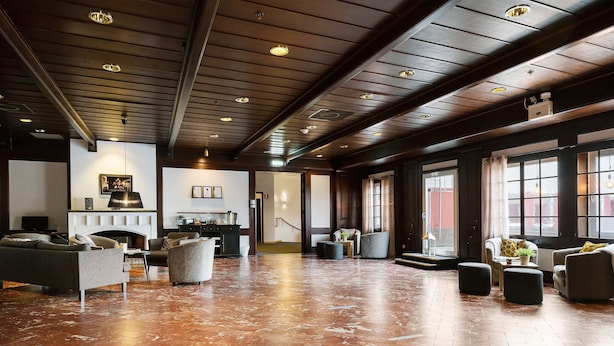 Un hall amplio con piso de madera pulida, mobiliario moderno y ventanas grandes que dejan entrar luz natural.