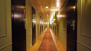 Un pasillo de hotel con suelo de madera y alfombra roja.