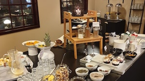 Un montaje de buffet con diversos alimentos, bebidas y utensilios sobre una mesa larga.