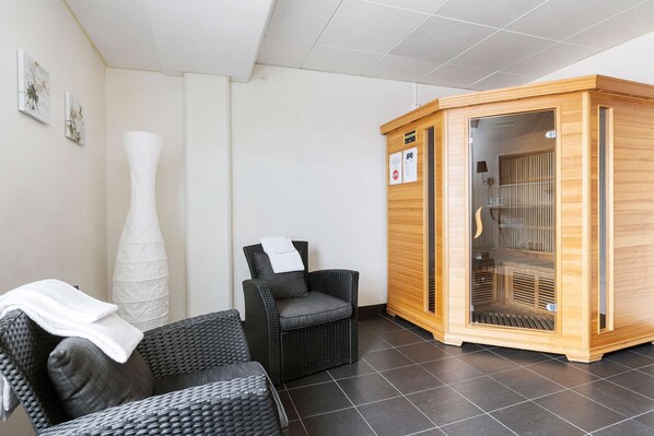 A room with a massage chair, a wooden sauna, and a white sculpture.