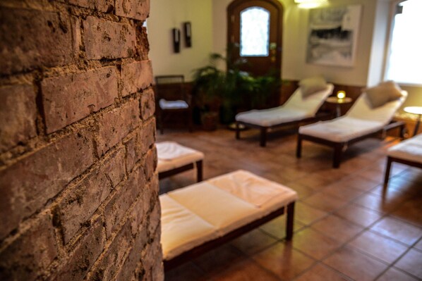 Un área de spa con pared de ladrillo, sillones de descanso y puerta de madera.