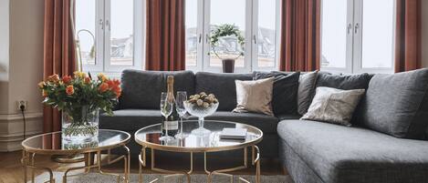 A modern living room with a grey sofa, two round coffee tables, and a large window with curtains.