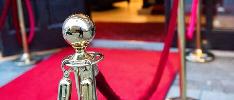 Una alfombra roja que conduce a una puerta con una barrera de seguridad.