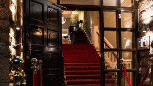 Una entrada imponente con alfombra roja, una escalera y un candelabro.
