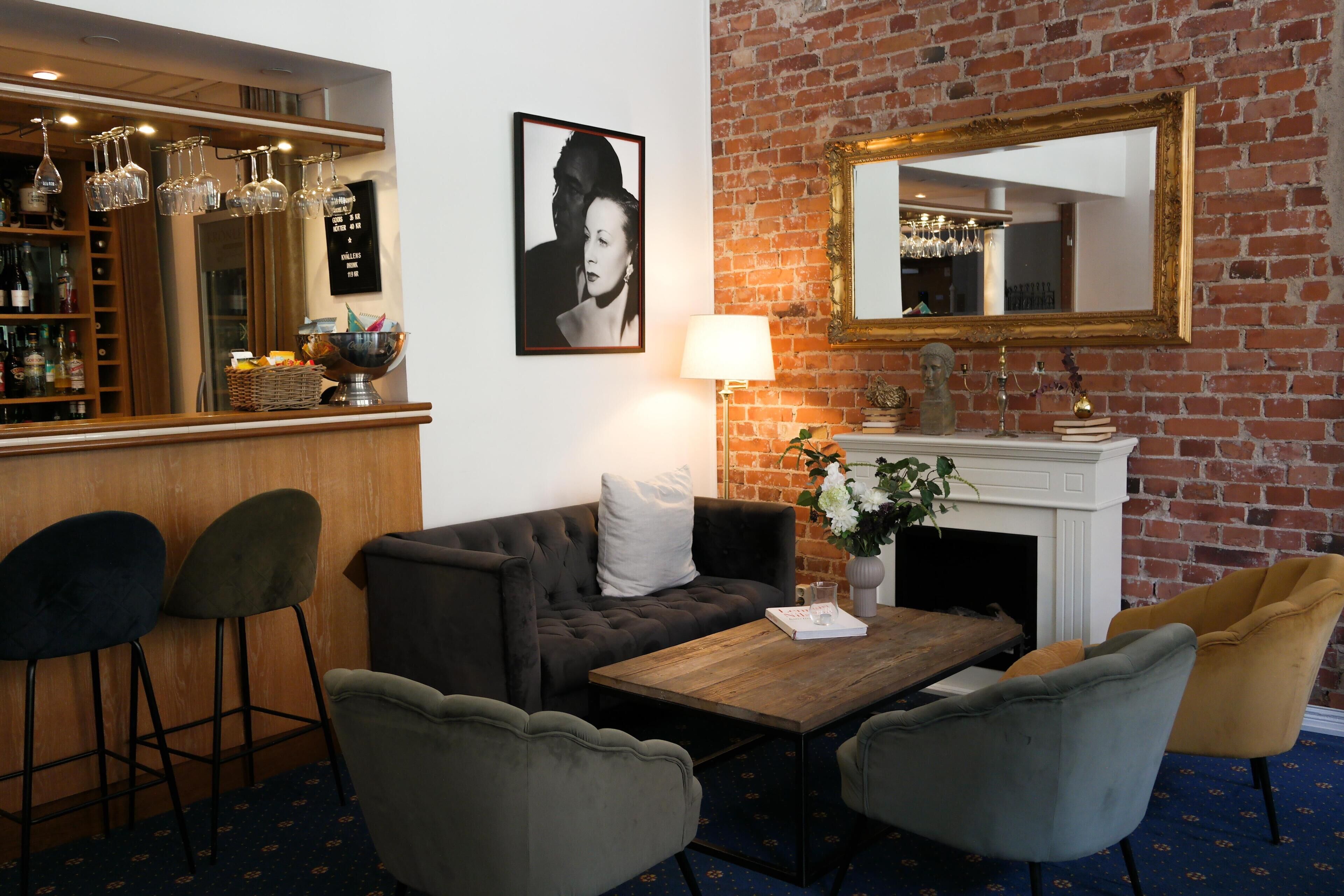 A bar area with stools, a fireplace, and a mirror on a brick wall.