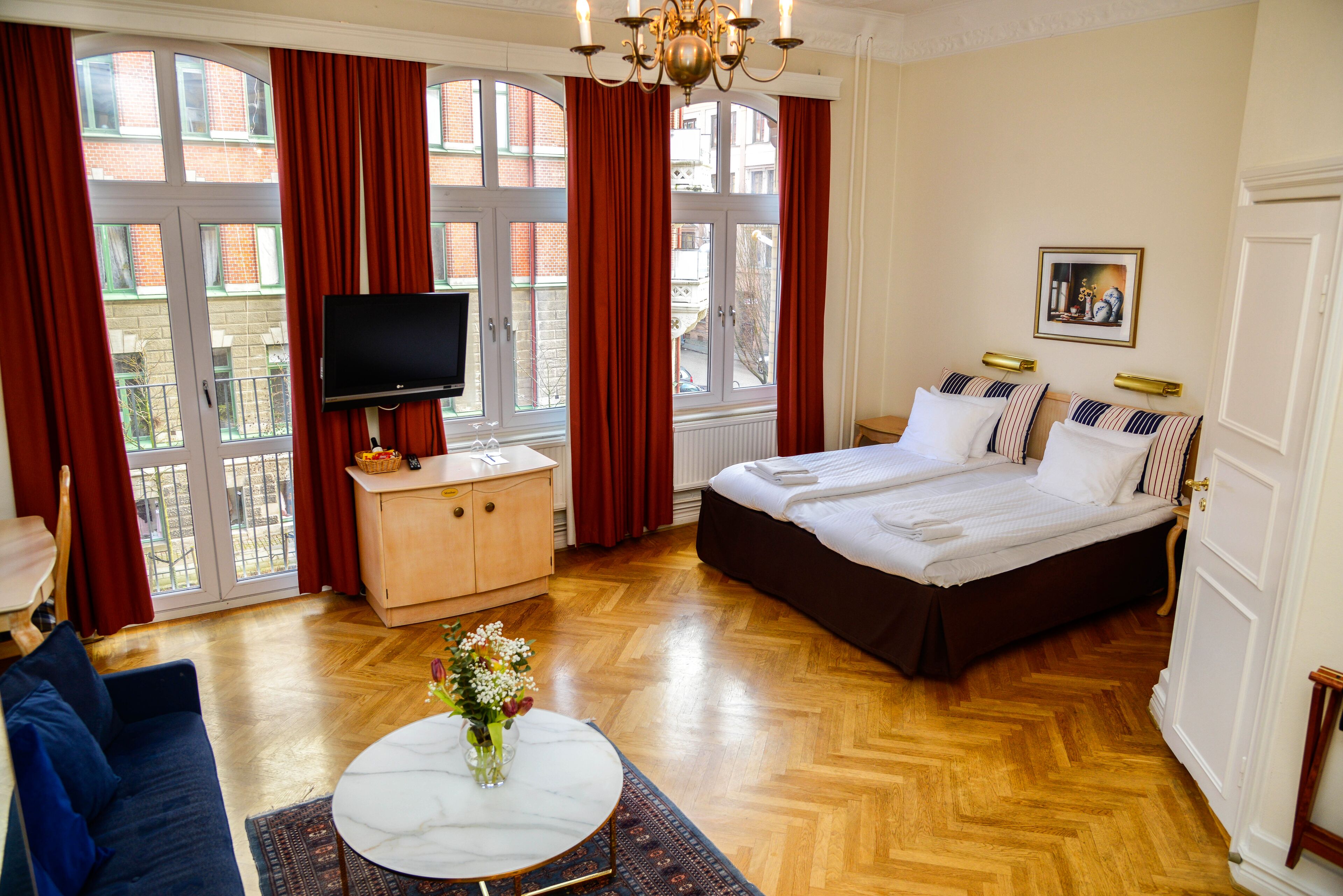Een hotelkamer met een groot bed, een televisie, een houten dressoir en uitzicht op het omliggende landschap.