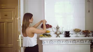 A woman arranging flowers on a white tiled kitchen counter with decorative elements and a window above.