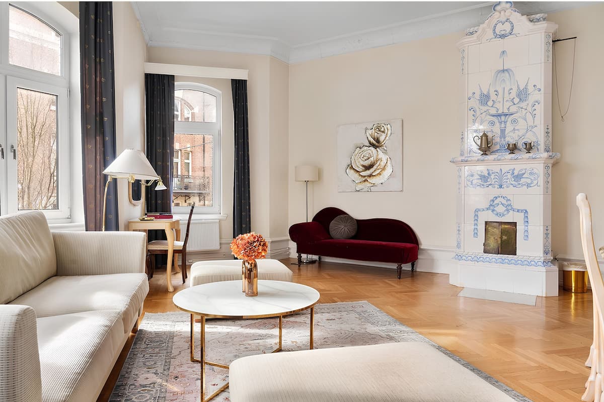 A living room with a sofa, a red armchair, a coffee table, and a fireplace.