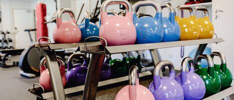 A rack of colorful kettlebells in a gym setting.